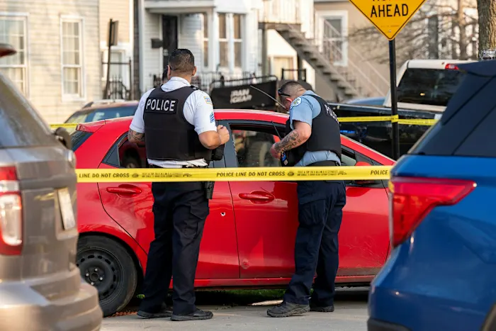Chicago police officers secure a red car that crashed into a fence in the 4500 block of South Marshfield Avenue suspected of being linked to a fatal shooting Tuesday, May 10, 2022 in Chicago  