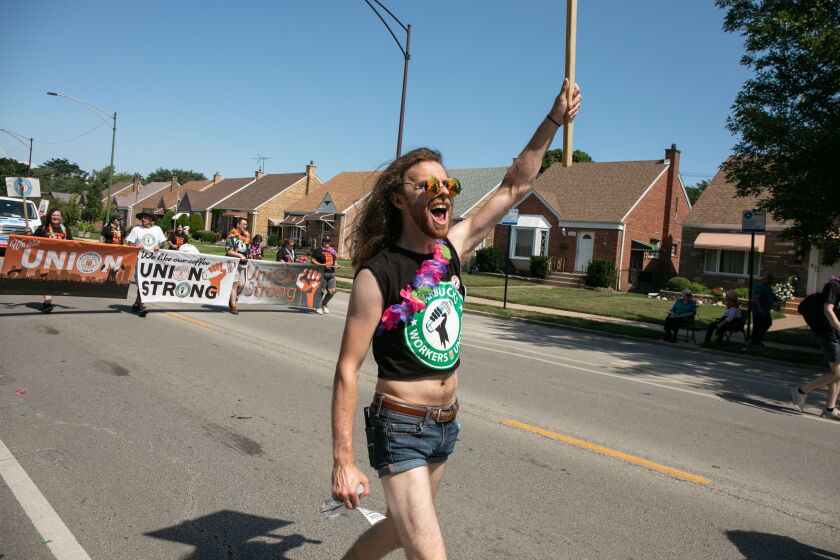 Starbucks shift supervisor J. Alan walks along Ewing Avenue in the East Side neighborhood Saturday during Chicago's Labor Day Parade.